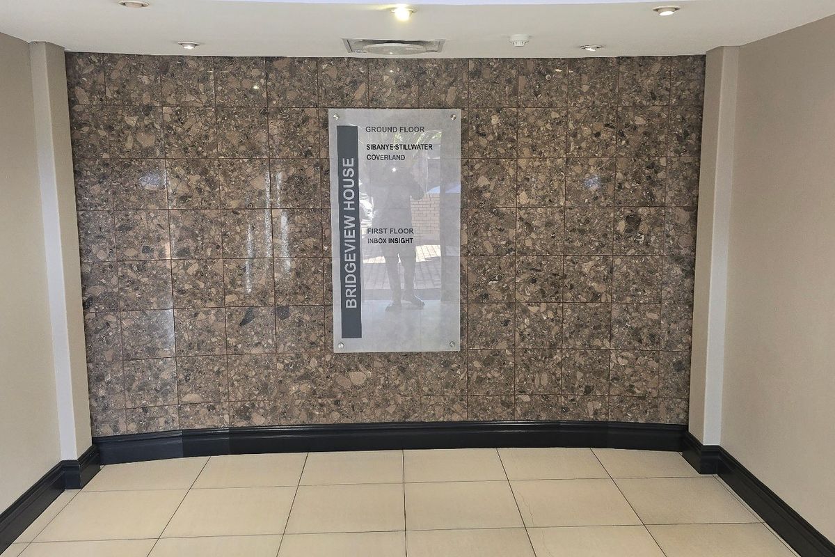 A clean and professional commercial building entrance lobby featuring a stone-tiled feature wall with integrated directory signage and recessed ceiling lighting.