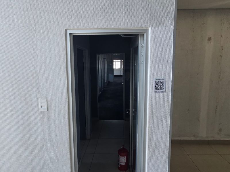 A view of an industrial hallway with tiled flooring and visible wall surface wear, requiring maintenance and cosmetic updates.
