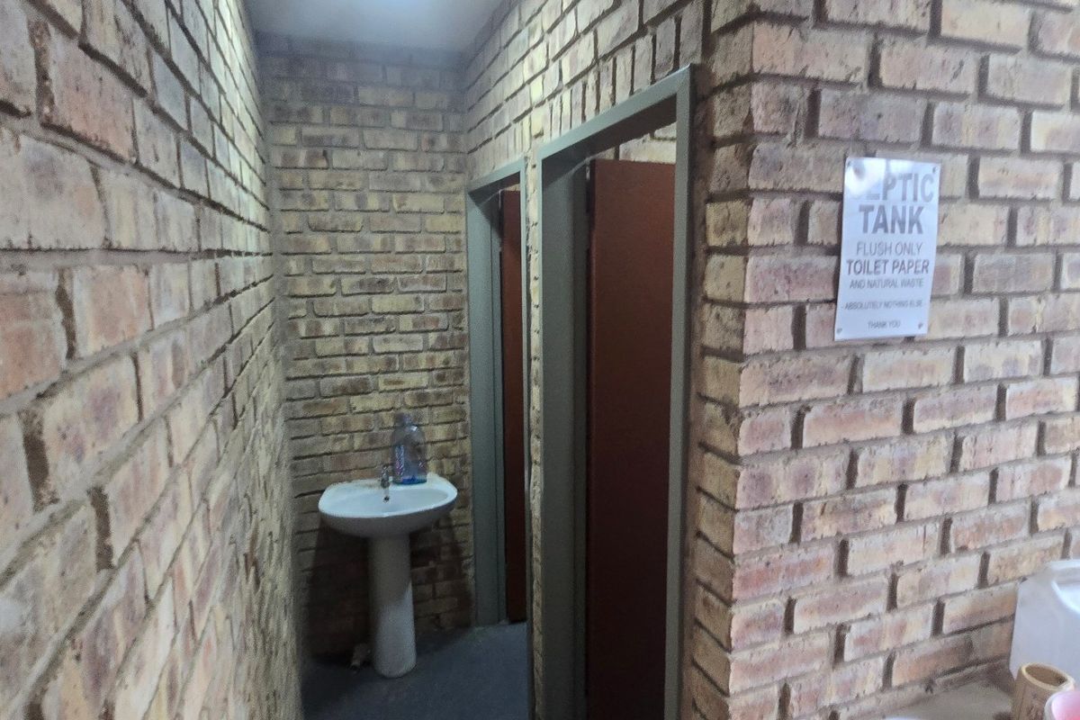 A functional bathroom area featuring exposed brick walls and a pedestal basin, providing basic utility within the industrial property.