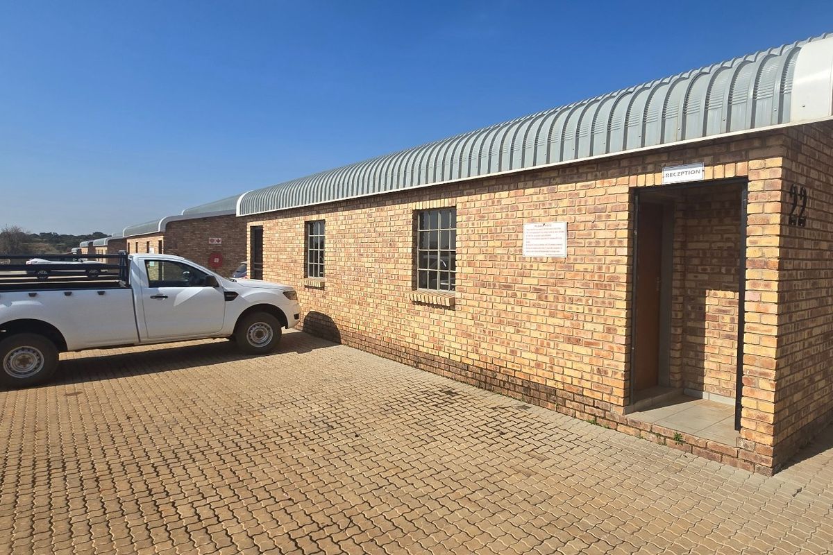 Industrial property exterior featuring a face brick facade, curved metal roofing, and a paved driveway area with a designated reception entrance.