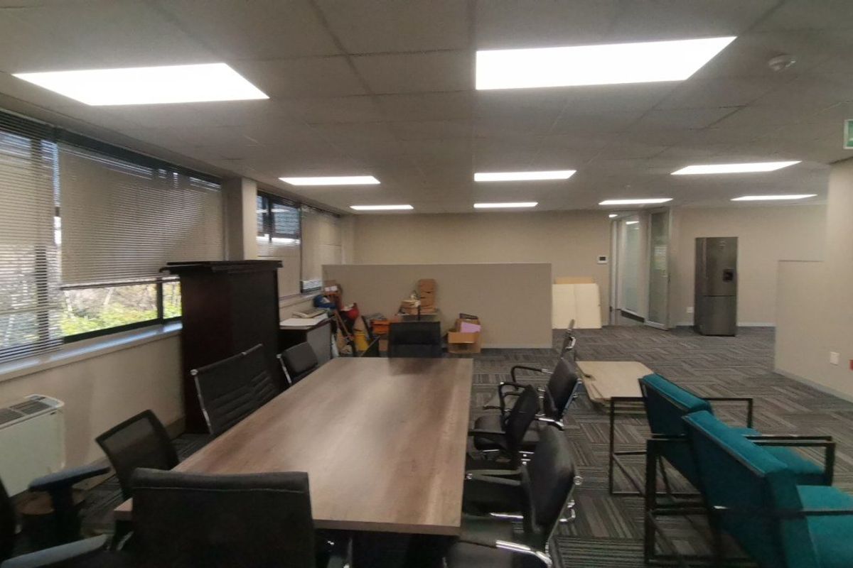 Open-plan commercial office space featuring suspended ceilings, recessed lighting, carpeted flooring, and partition walls, suitable for a professional work environment.