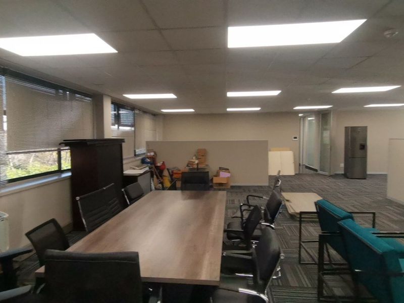 Open-plan commercial office space featuring suspended ceilings, recessed lighting, carpeted flooring, and partition walls, suitable for a professional work environment.