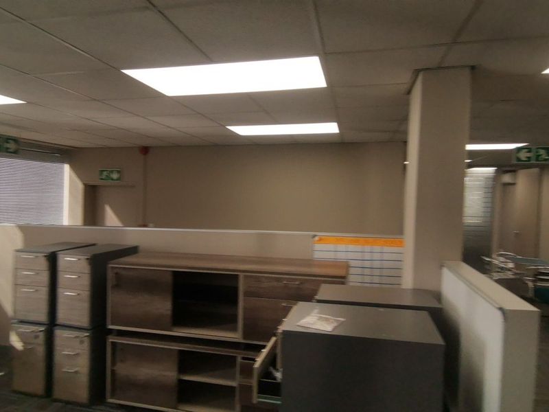 Open plan commercial office space featuring suspended ceilings, recessed lighting, and partition walls, currently requiring cosmetic updates to the flooring and ceiling finishes.