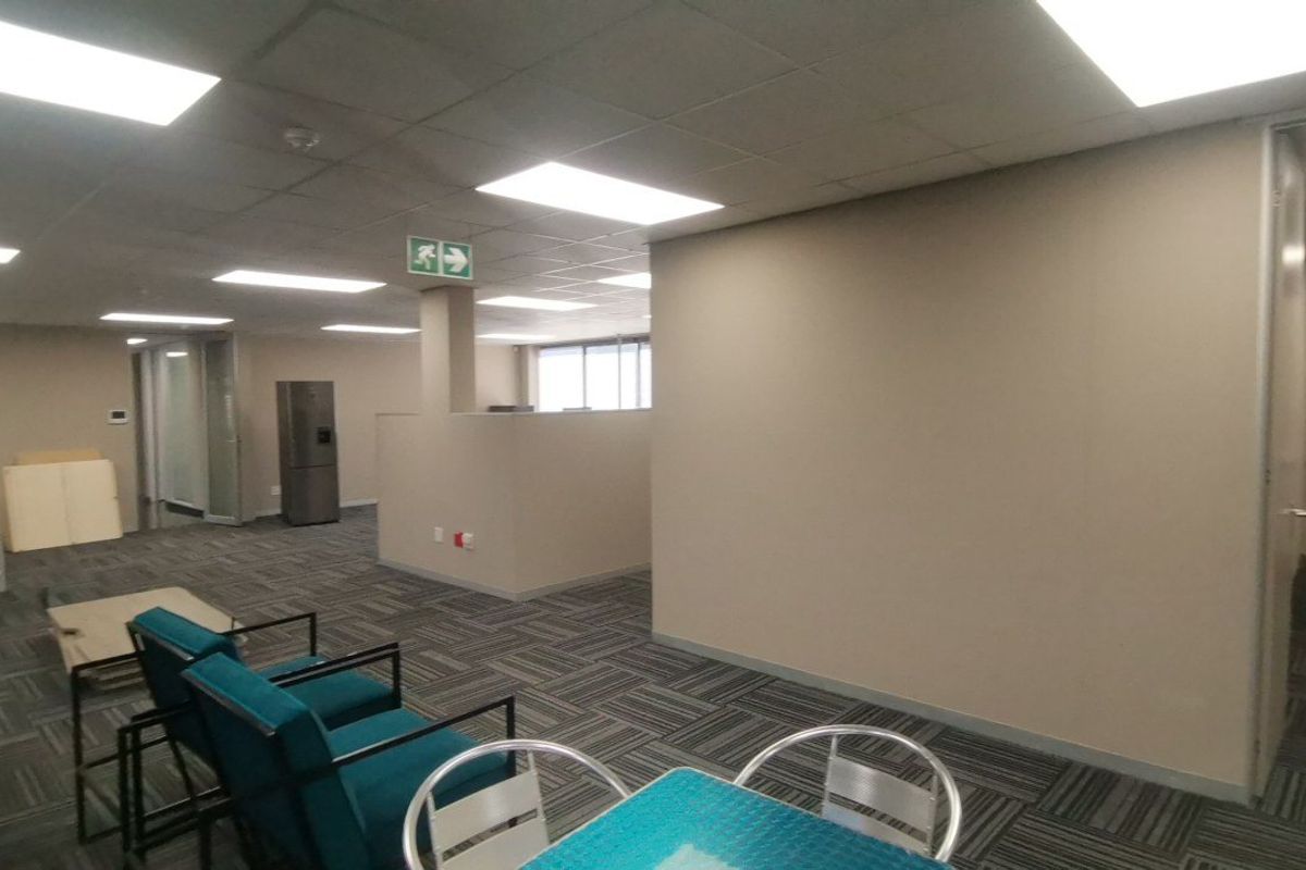 Open-plan commercial office space featuring suspended ceilings, recessed lighting, and neutral partition walls with durable carpeted flooring.