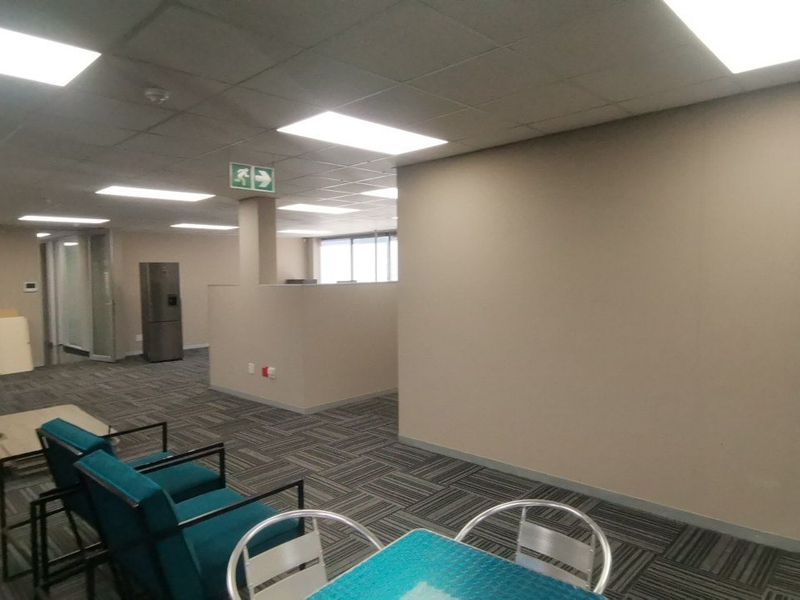 Open-plan commercial office space featuring suspended ceilings, recessed lighting, and neutral partition walls with durable carpeted flooring.