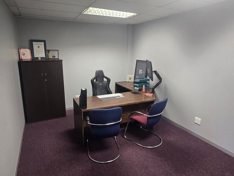 A functional commercial office space featuring neutral wall finishes, carpeted flooring, and a suspended ceiling with integrated lighting.