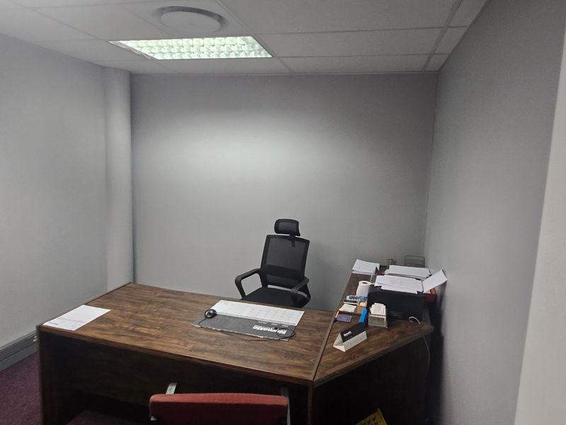 A functional commercial office space featuring a suspended ceiling with recessed lighting and neutral wall finishes.
