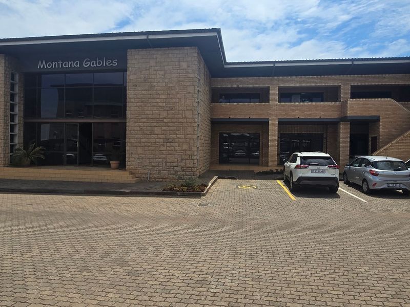 Front elevation of Montana Gables commercial building featuring stone and face brick facade with paved parking and covered entrance.
