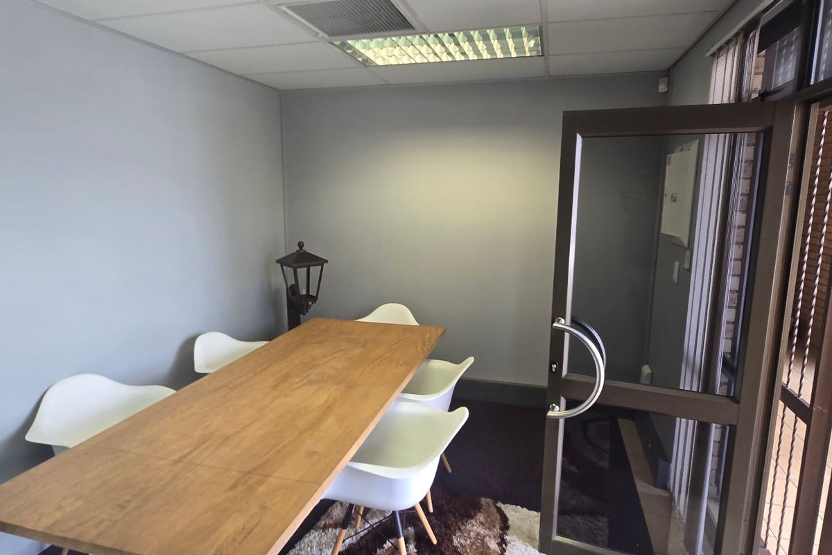 A functional office space featuring a suspended ceiling with recessed lighting and an aluminium-framed glass entrance door.