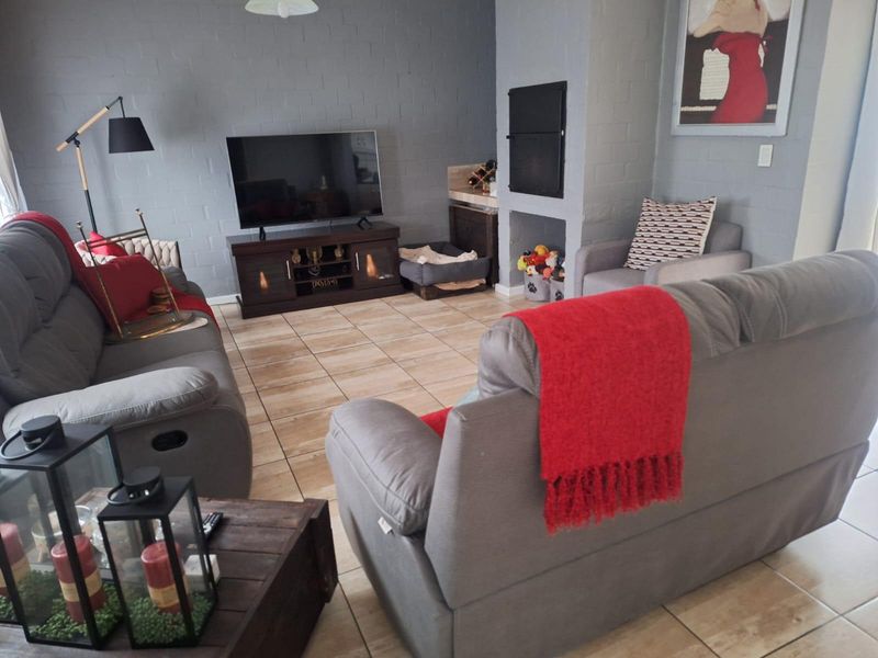 A comfortable living room featuring painted brick walls, tiled flooring, and a built-in fireplace, creating a cozy and functional space.