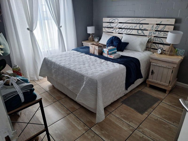 A cozy bedroom featuring tiled flooring and a painted brick feature wall, creating a comfortable and inviting sleeping space.