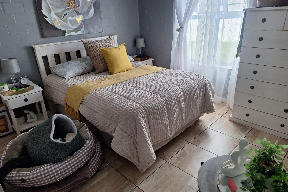 A well-maintained bedroom featuring tiled flooring and painted brick walls, offering a cozy and functional living space.