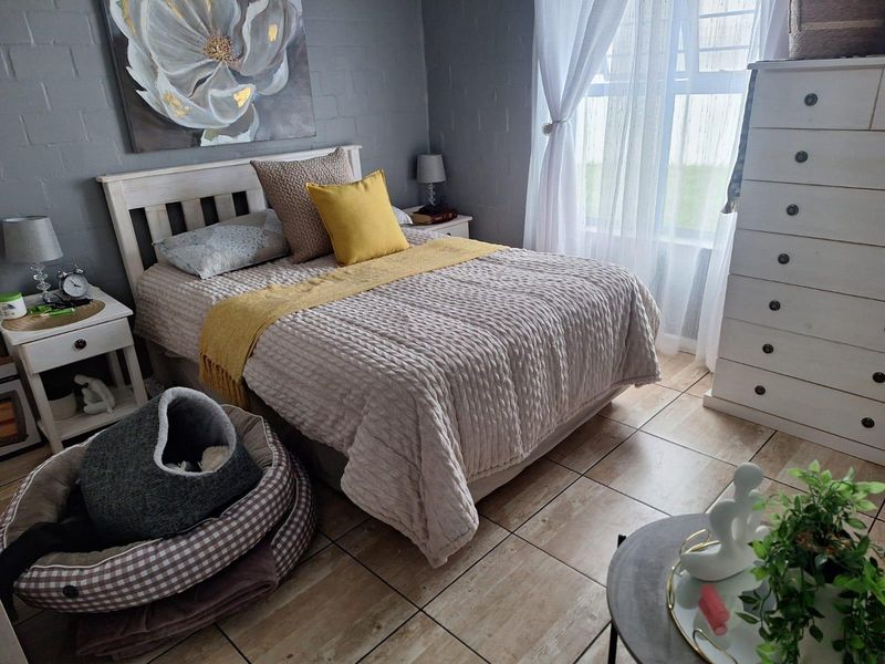 A well-maintained bedroom featuring tiled flooring and painted brick walls, offering a cozy and functional living space.
