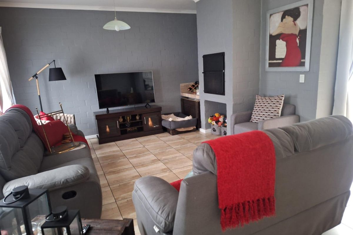 A comfortable living room featuring tiled flooring and a built-in fireplace, finished with neutral grey painted brick walls.