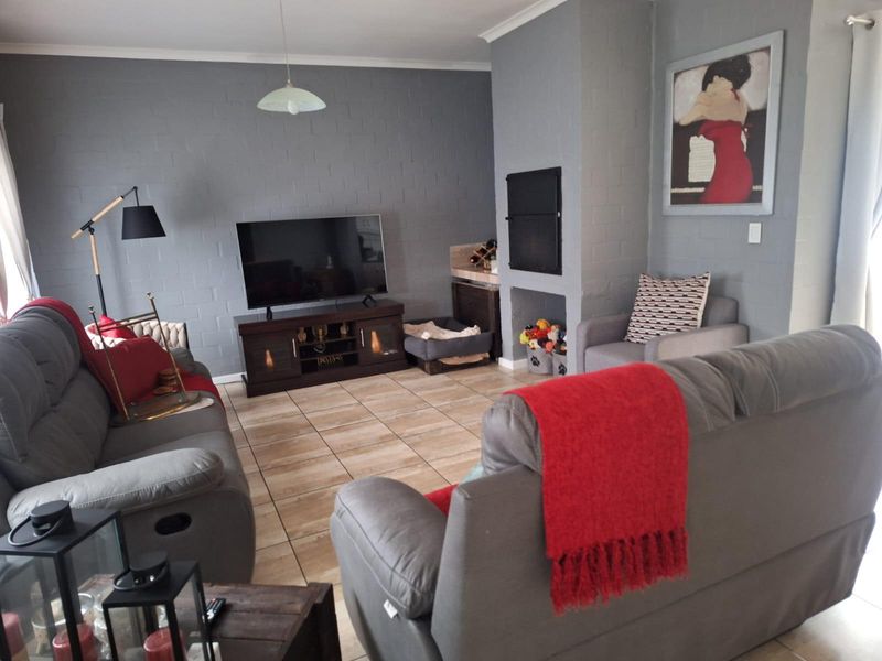 A comfortable living room featuring tiled flooring and a built-in fireplace, finished with neutral grey painted brick walls.
