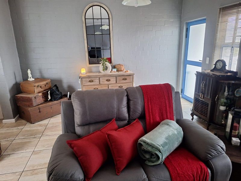 A living room featuring painted brick walls and tiled flooring, with direct access to an external door.