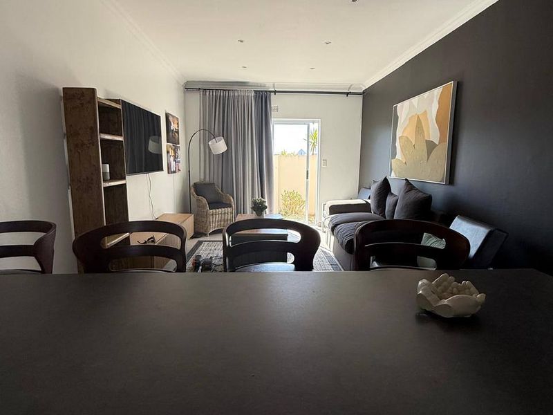 An open-plan living area featuring a modern dark accent wall, recessed lighting, and a sliding door providing access to the outdoor space.