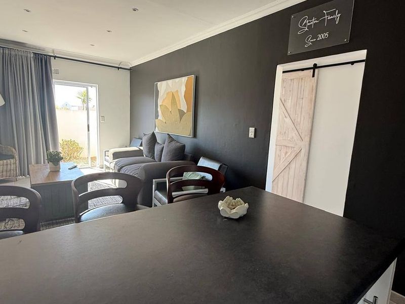 Open plan living area featuring a kitchen island, modern dark accent wall, and a sliding barn door leading to adjacent space.