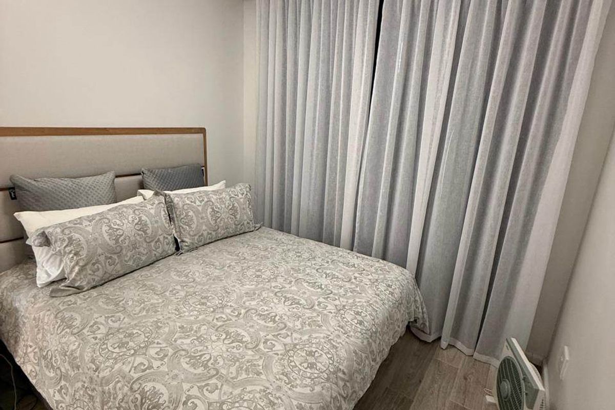 A well-maintained bedroom featuring modern laminate flooring and floor-to-ceiling curtain treatments.