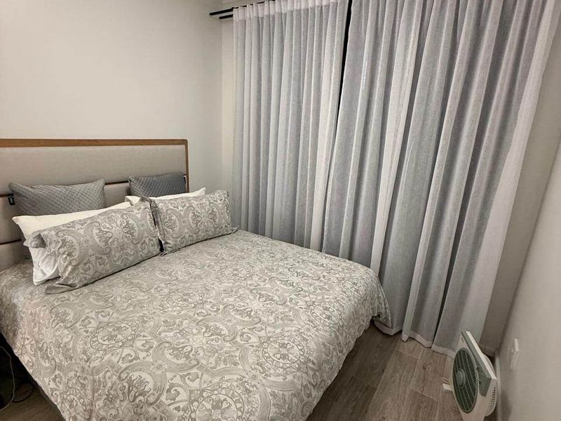 A well-maintained bedroom featuring modern laminate flooring and floor-to-ceiling curtain treatments.