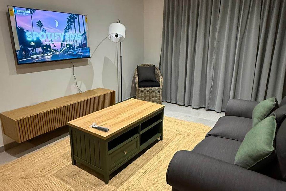 A modern living room featuring recessed downlighting, tiled flooring, and full-length curtains, creating a comfortable and well-maintained space.