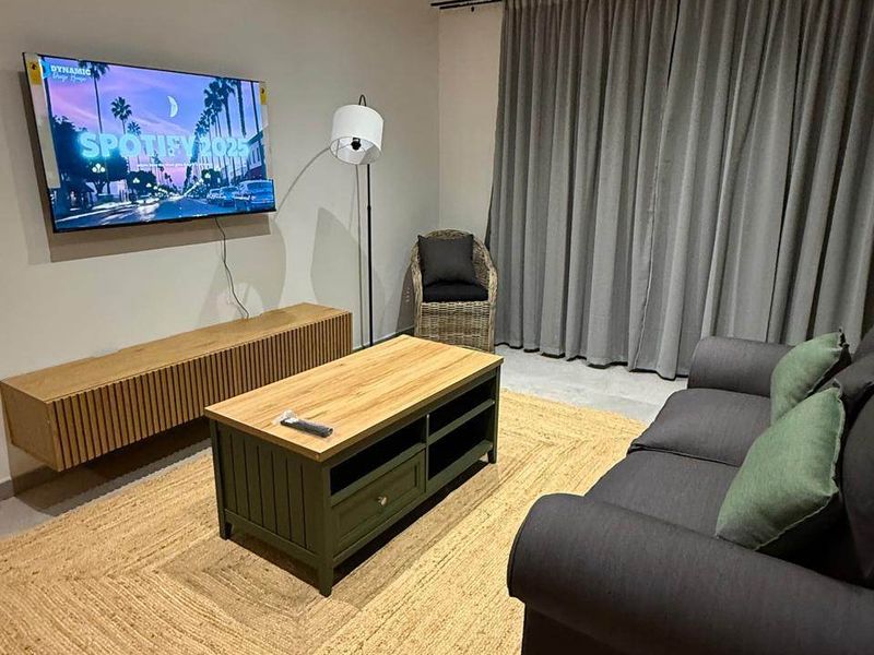 A modern living room featuring recessed downlighting, tiled flooring, and full-length curtains, creating a comfortable and well-maintained space.