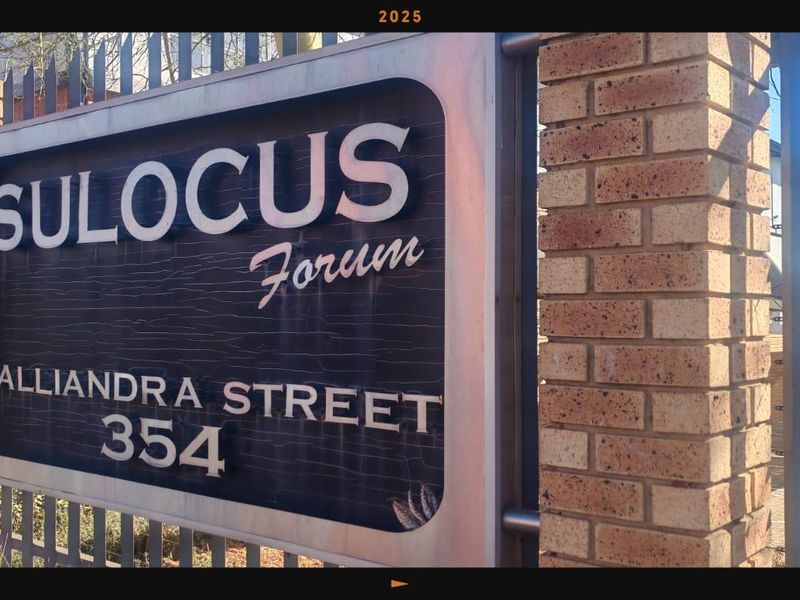 Exterior view of the Sulocus Forum property entrance, featuring brick pillars and metal security fencing.