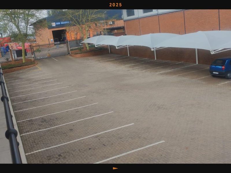 Commercial parking area featuring paved bays, shade cloth carports, and secure gated access.