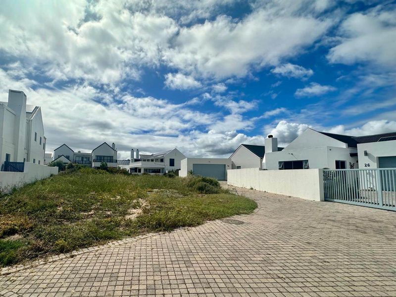 Front view of the property featuring a paved driveway, boundary wall with gate, and access to the garage.