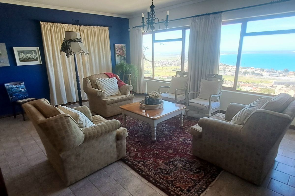 A comfortable living room featuring large windows that offer expansive coastal views, tiled flooring, and a classic layout.