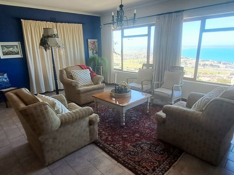 A comfortable living room featuring large windows that offer expansive coastal views, tiled flooring, and a classic layout.