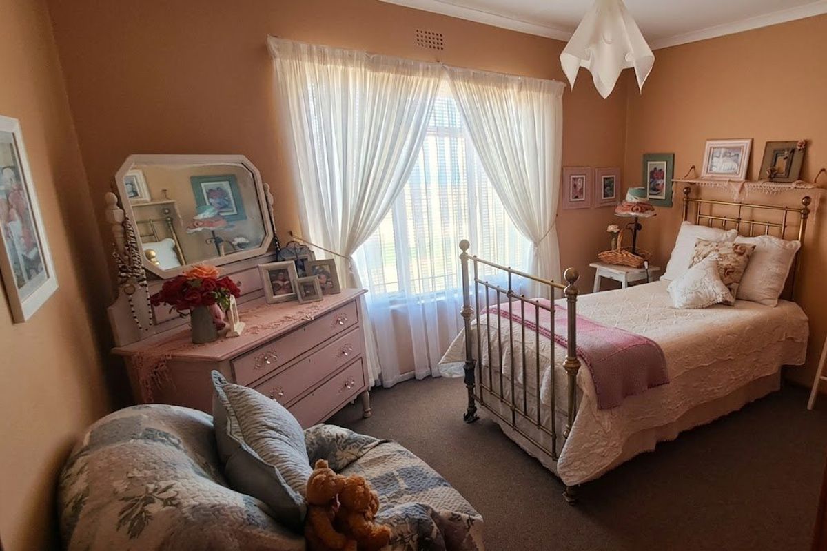 A cozy bedroom featuring carpeted flooring, neutral wall tones, and a large window with curtain treatments, providing a comfortable and functional living space.