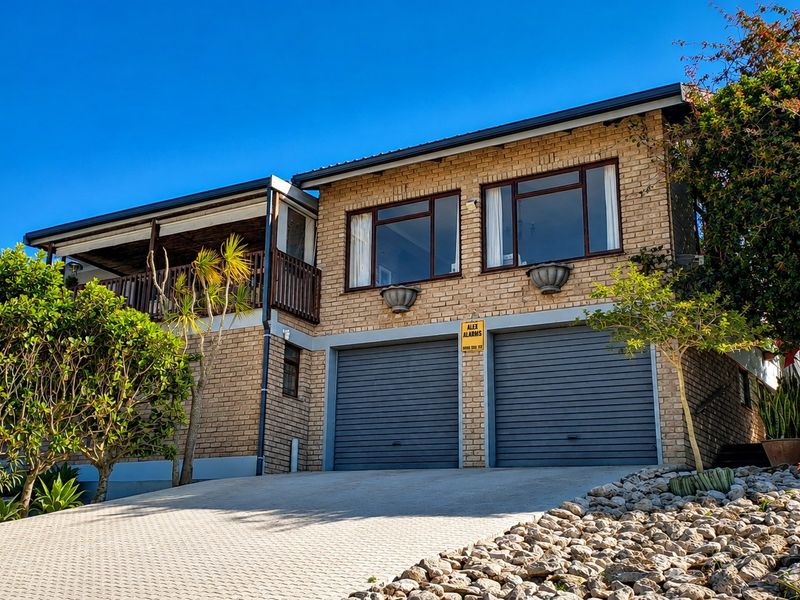 Front elevation of a double-story brick house featuring a double garage with roller doors, a paved driveway, and an upper-level balcony.