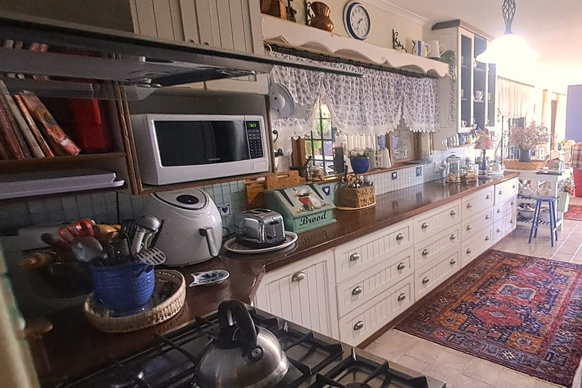A traditional country-style kitchen featuring timber cabinetry, tiled splashbacks, timber countertops, and a gas hob with an integrated extractor fan.
