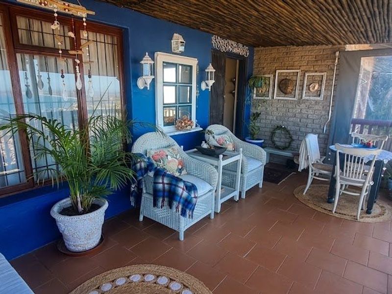 A covered patio featuring a thatched ceiling, terracotta tiled flooring, and an exposed brick feature wall, offering a comfortable outdoor living space.