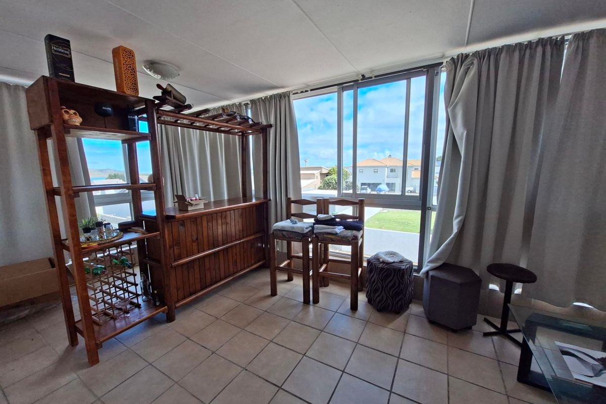 A living area featuring tiled flooring and a large sliding window that provides natural light and views of the surrounding neighborhood.
