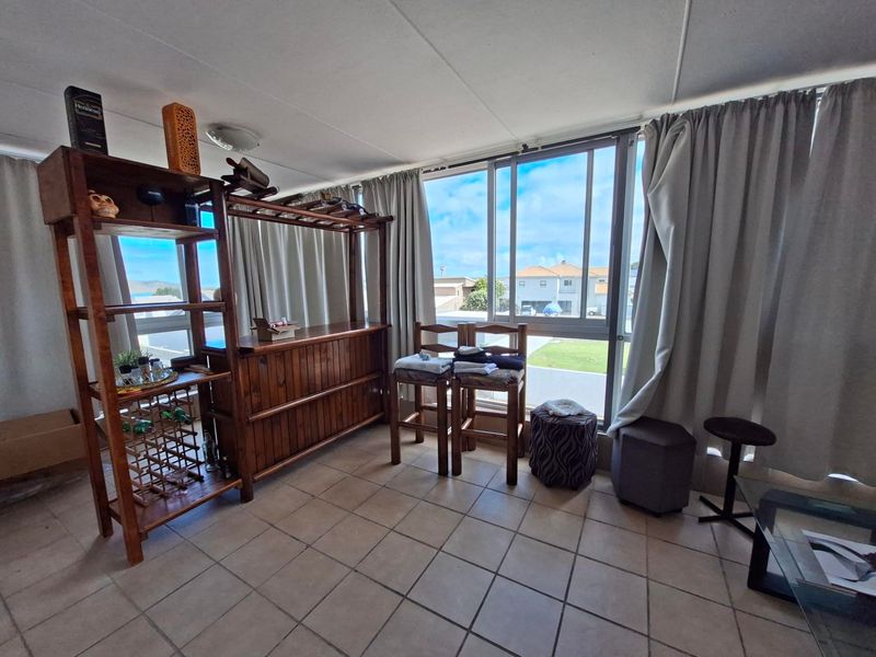 A living area featuring tiled flooring and a large sliding window that provides natural light and views of the surrounding neighborhood.