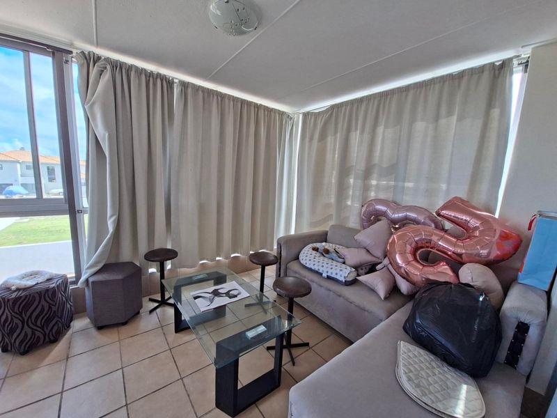 A bright living area featuring tiled flooring and a large sliding glass door that provides ample natural light.