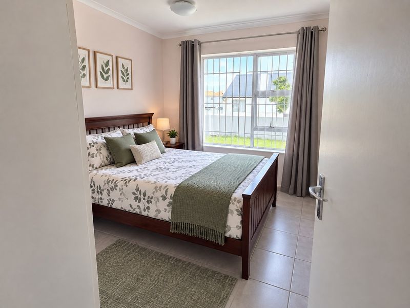 A well-maintained bedroom featuring tiled flooring, a large window with security bars, and neutral wall finishes.