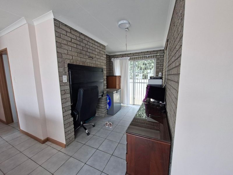 A living area featuring exposed brick walls, tiled flooring, and a sliding glass door providing access to the exterior.