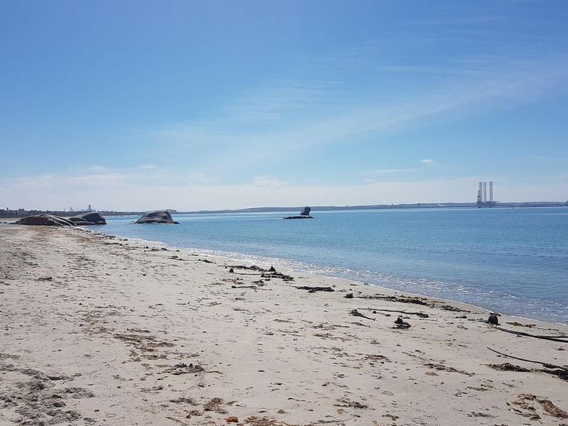 A scenic view of the sandy beach and calm ocean waters, showcasing the natural coastal landscape of the property.