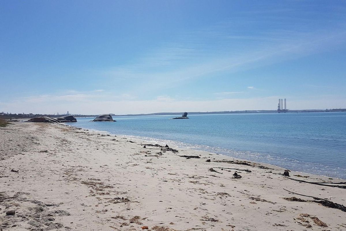 A scenic view of the sandy beach and calm ocean waters, showcasing the natural coastal landscape of the property.
