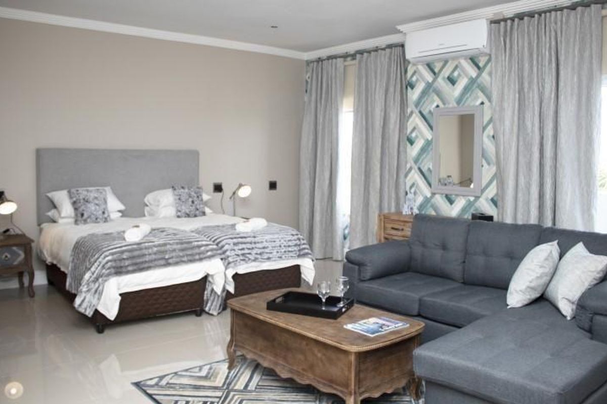 Spacious bedroom featuring tiled flooring, a wall-mounted air conditioning unit, and large windows with floor-to-ceiling curtains.