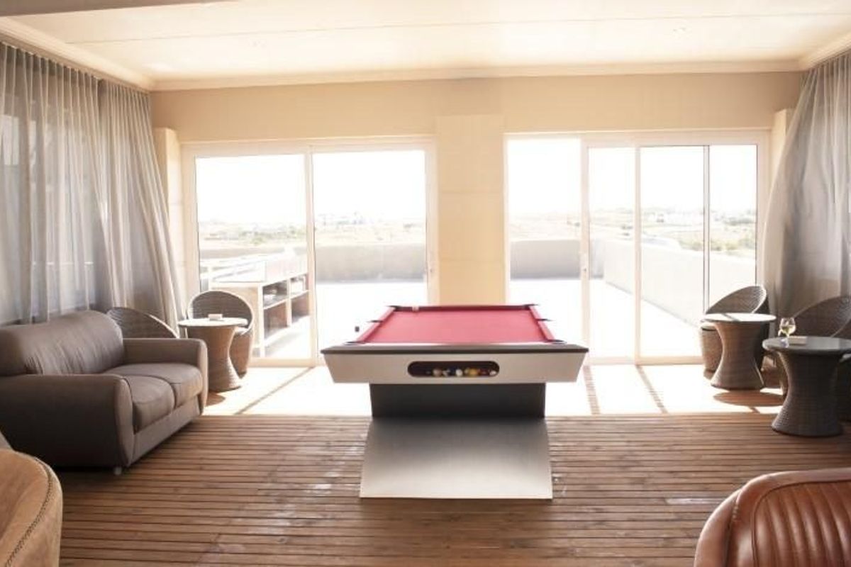 Spacious indoor entertainment area featuring timber decking, large sliding glass doors, and direct access to an outdoor patio.