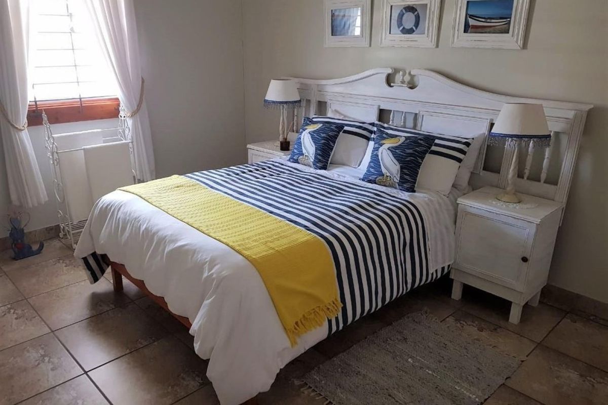 A cozy bedroom featuring tiled flooring and a window with natural light, providing a comfortable and functional living space.