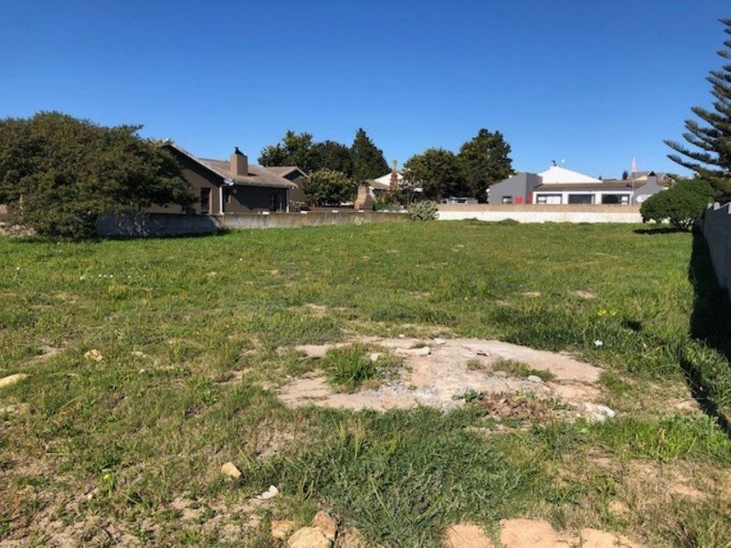 A vacant residential plot of land featuring a boundary wall and established grass, offering a clear space for potential development.