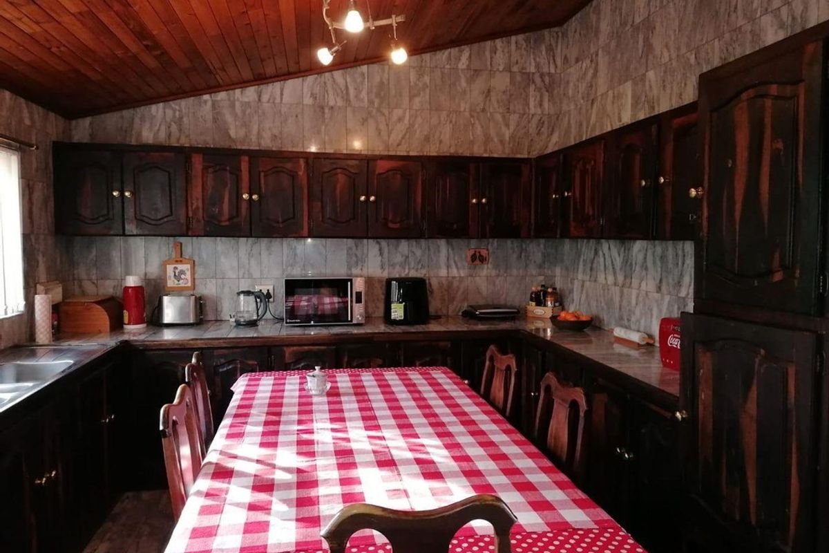 A traditional kitchen featuring dark wood cabinetry, marble-effect wall tiling, and a vaulted timber ceiling, providing a rustic and functional cooking space.
