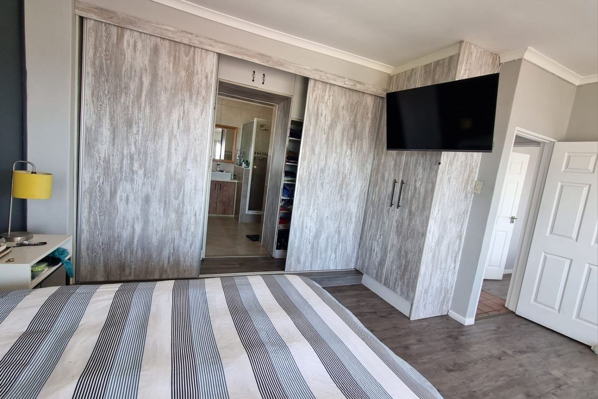 Bedroom featuring built-in wood-look sliding wardrobes with integrated shelving and an en-suite bathroom access.