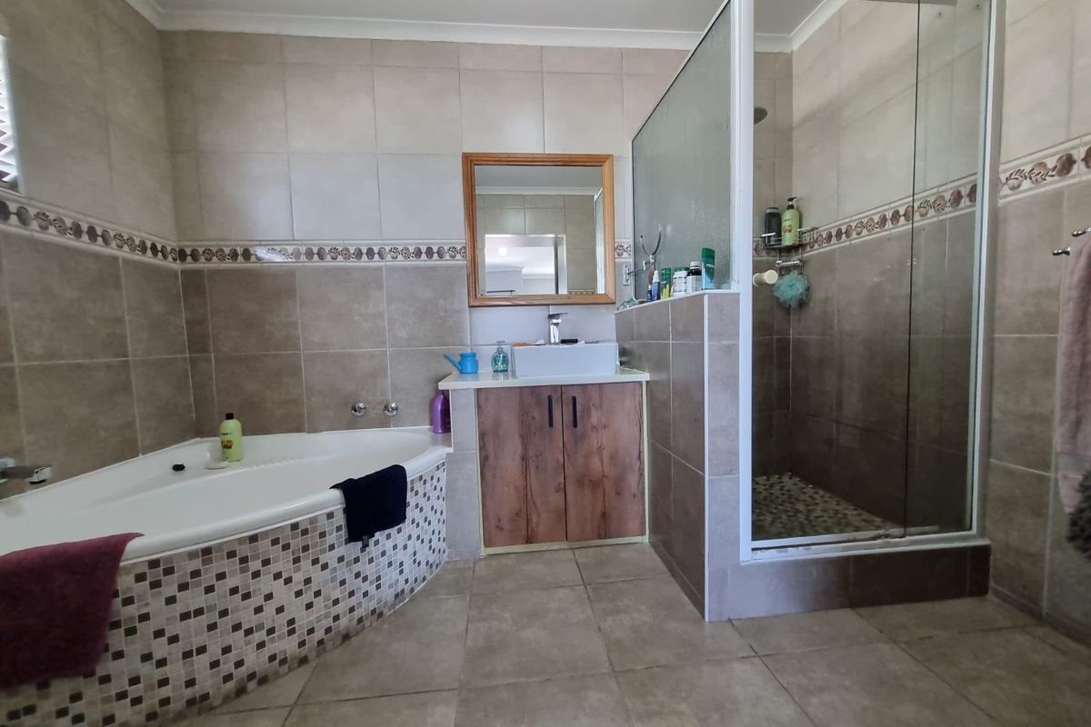 A functional bathroom featuring a corner bathtub, a separate glass-enclosed shower, and a vanity cabinet with a basin.