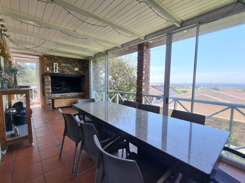 Covered patio area featuring a built-in brick braai, tiled flooring, and large glass sliding doors offering expansive views.